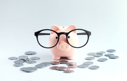 Piggybank,wearing,eyeglasses,on,office,table,with,heap,of,coins.